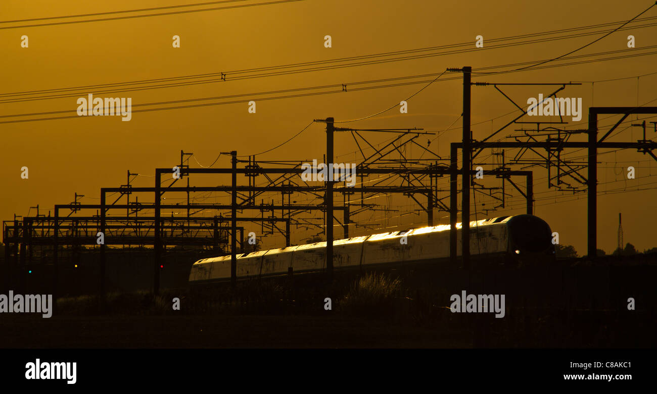 Jungfrau-Züge Pendolino-Zug fängt die Sonne glitzern der späten Abendsonne, Huddlesford, Lichfield, Staffordshire, England. Stockfoto