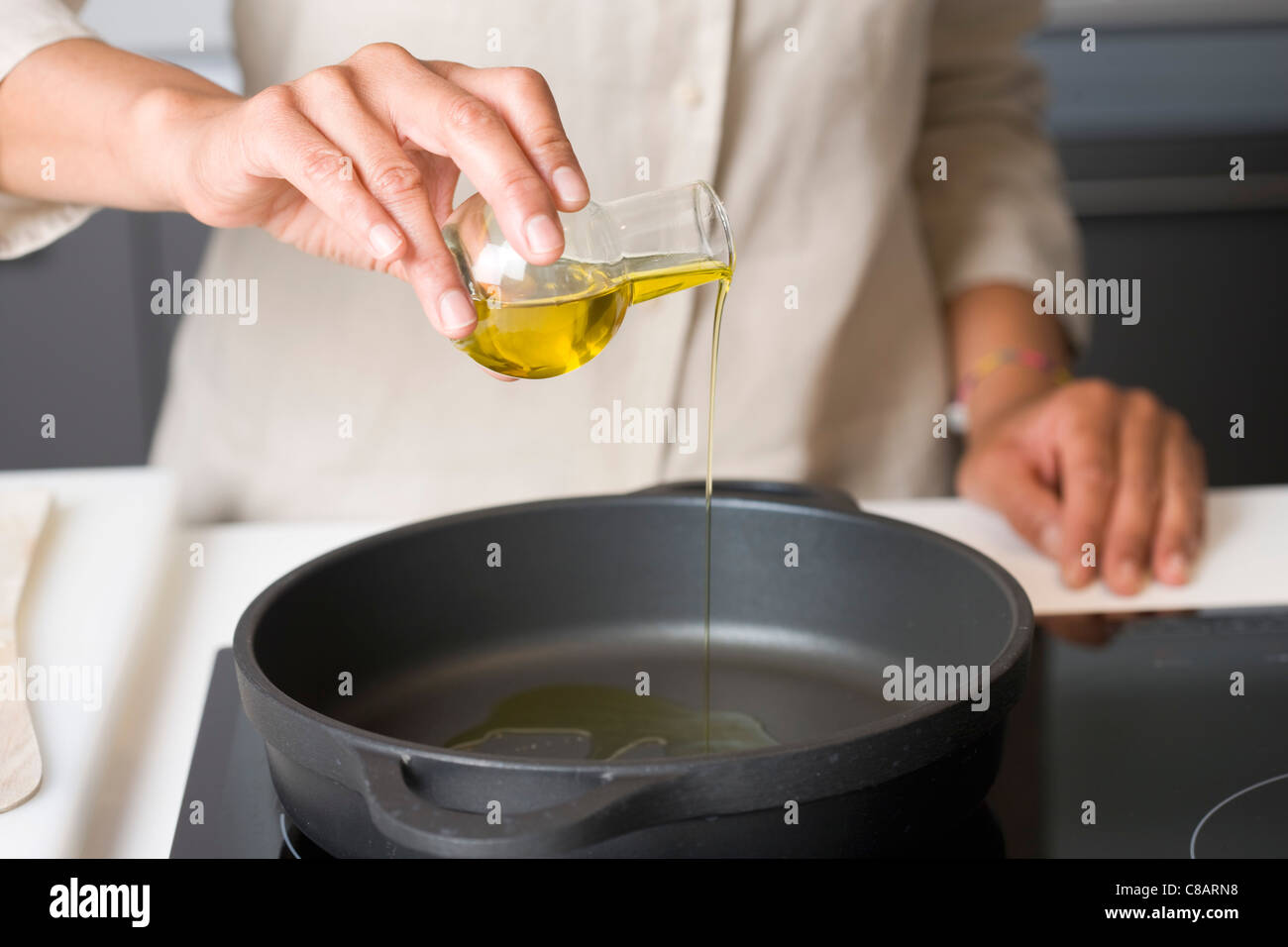 Etwas Olivenöl Gießen in einer Pfanne Stockfoto