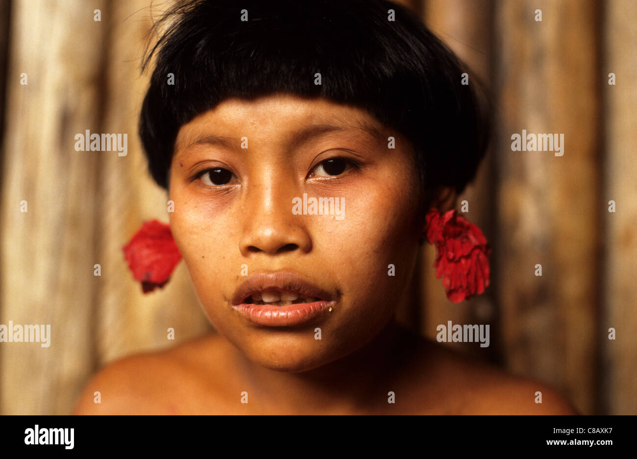 Roraima, Brasilien. Yanomami-Teenager-Mädchen mit roten Blume Ohr Stecker. Stockfoto
