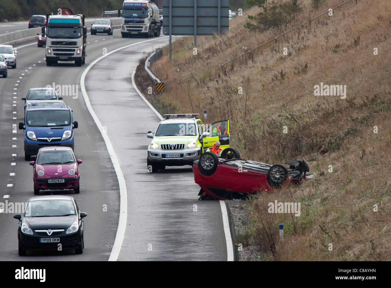 Eine umgekehrte Kfz liegt auf dem Dach auf dem Standstreifen der Autobahn M42 nahe Verzweigung 10. Stockfoto