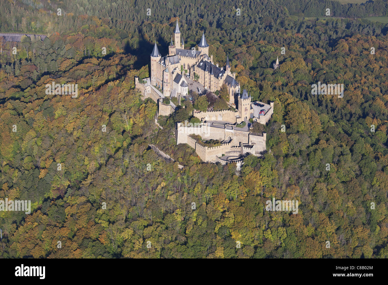 LUFTAUFNAHME. Schloss auf einem bewaldeten Hügel mit herbstlichen Farben. Schloss Hohenzollern, Hechingen, Baden-Württemberg, Deutschland. Stockfoto