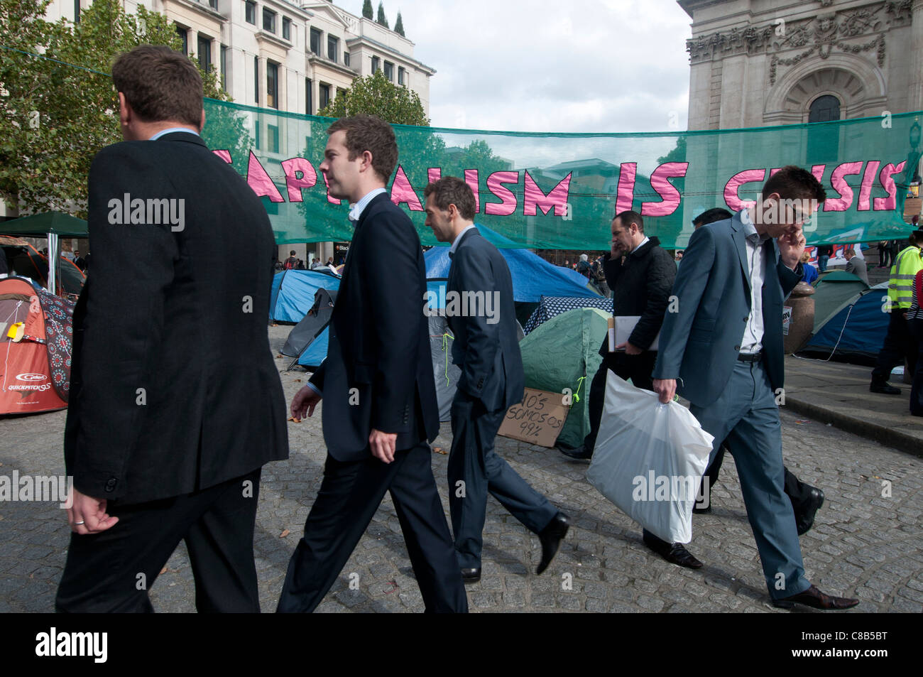 London i. Teil des weltweiten Protest zu besetzen. Stadtarbeiter pass durch das Lager und Banner, die sagen, dass Kapitalismus Krise ist. Stockfoto