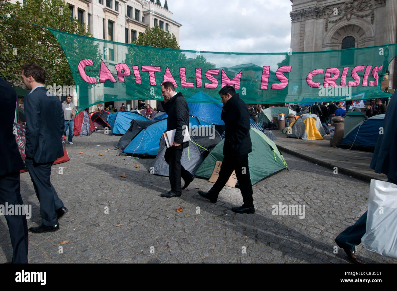London i. Teil des weltweiten Protest zu besetzen. Stadtarbeiter pass durch das Lager und Banner, die sagen, dass Kapitalismus Krise ist. Stockfoto