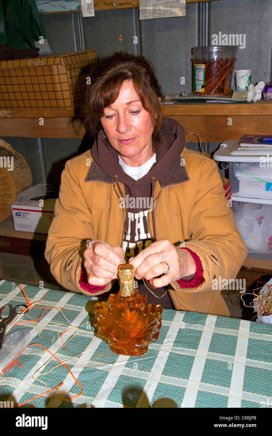 Arbeiter, die Etikettierung von Flaschen Ahornsirup in einer Zuckerhütte am See Odessa, Michigan, USA. Stockfoto