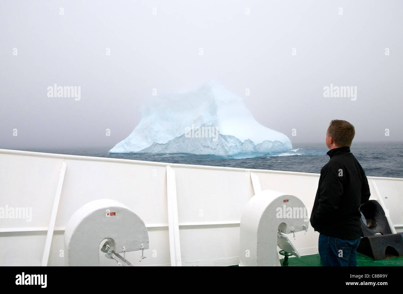 Einen männlichen Touristen stehen auf dem Deck des Schiffes Antarktis-Expedition der MV Ushuaia Blick auf einem Eisberg im südlichen Ozean Stockfoto