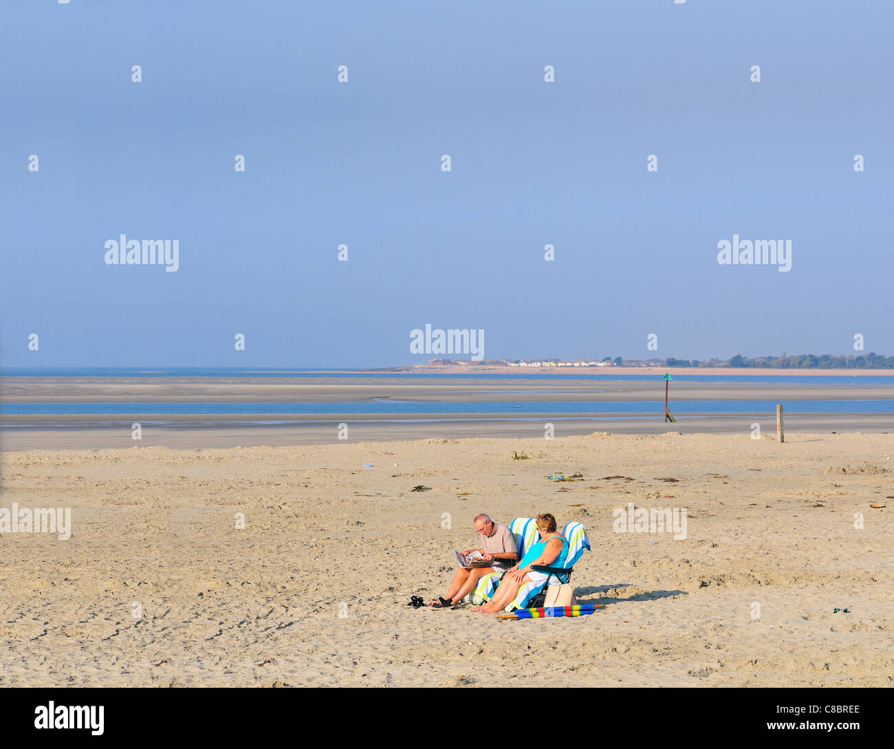 Zwei Leute sonnen sich und genießen das Oktoberwetter an einem ungewöhnlich leeren Strand in West Wittering, West Sussex, England, Großbritannien Stockfoto