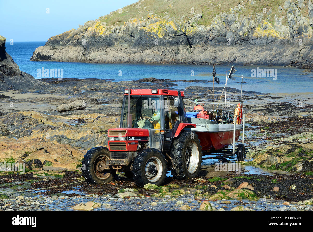 Ein Fischer mit einem Traktor um zu bewegen sein Boot am felsigen Strand von Port Quin in Nord Cornwall, Großbritannien Stockfoto