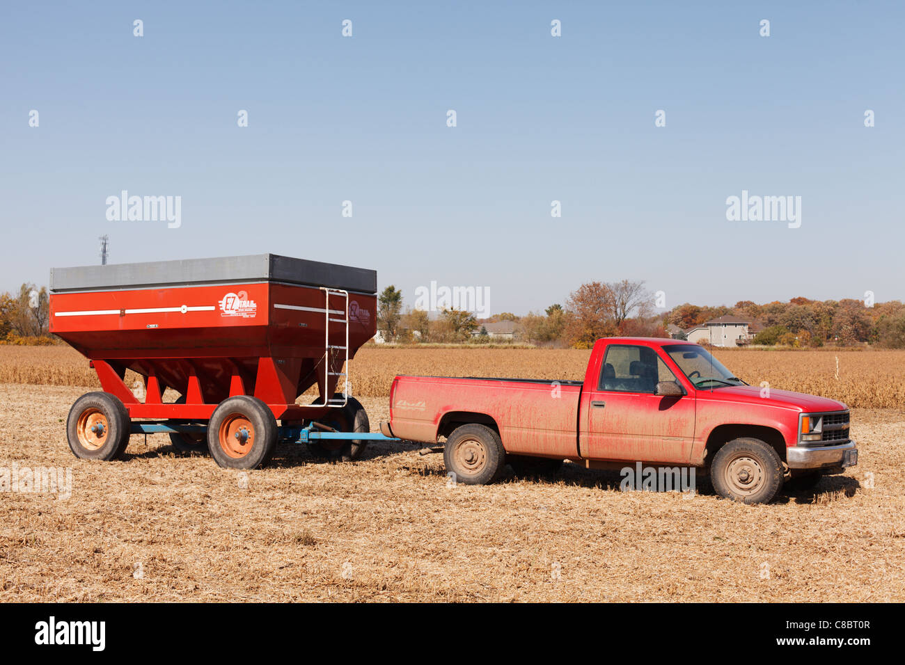 Einen roten Pickup und Getreide Wagen in einem Bauernhof Feld, Minnesota, USA. Stockfoto