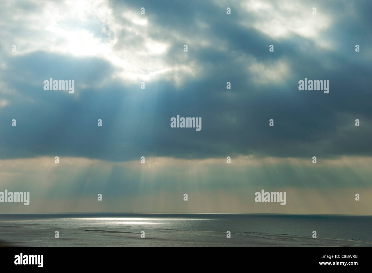 Gewitterwolken und Sonnenstrahlen über Meer Stockfoto