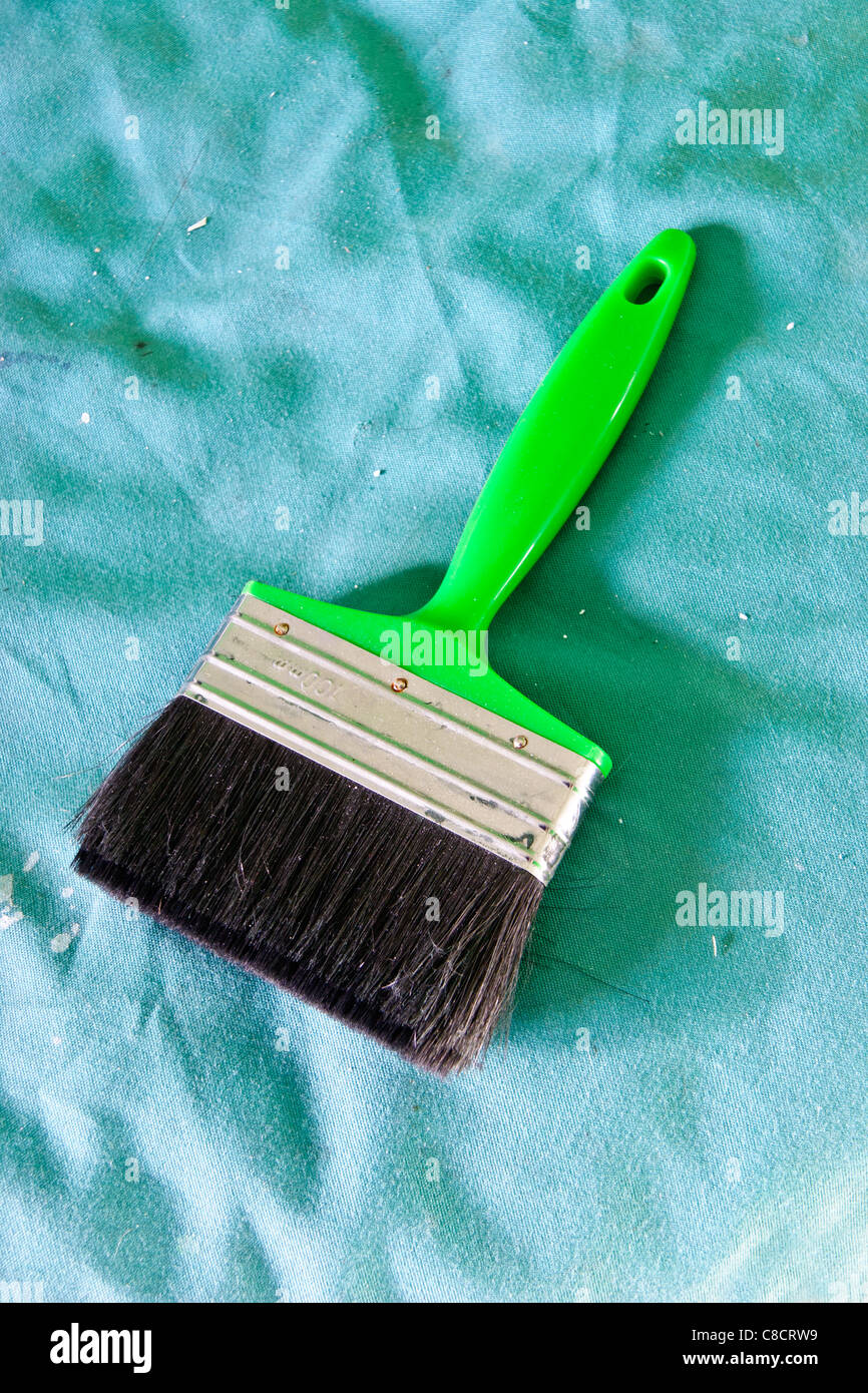 Pinsel mit grünem Griff auf einem grünen Leinwand Blatt Stockfoto