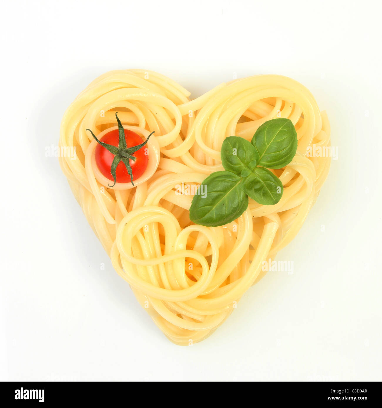 Gesunde Ernährung, Spaghetti in Form eines Herzens mit Tomaten und Basilikum auf weißem Hintergrund Stockfoto