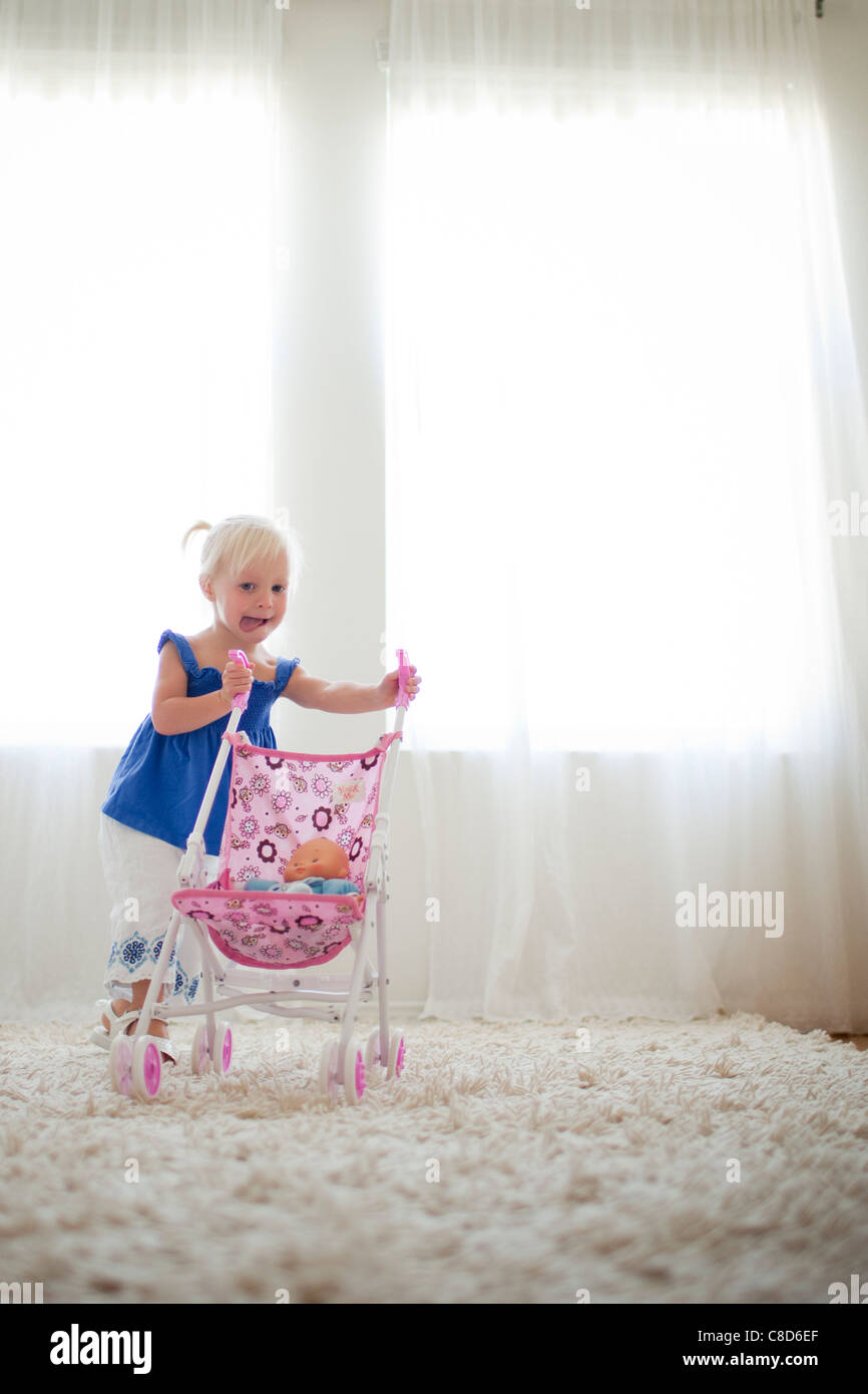 Kleinkind Mädchen schieben Spielzeug Kinderwagen mit Baby-Puppe Stockfoto