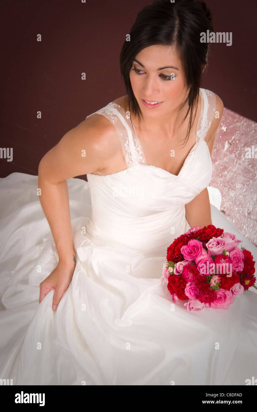 Braut sitzt mit Blumenstrauß Stockfoto