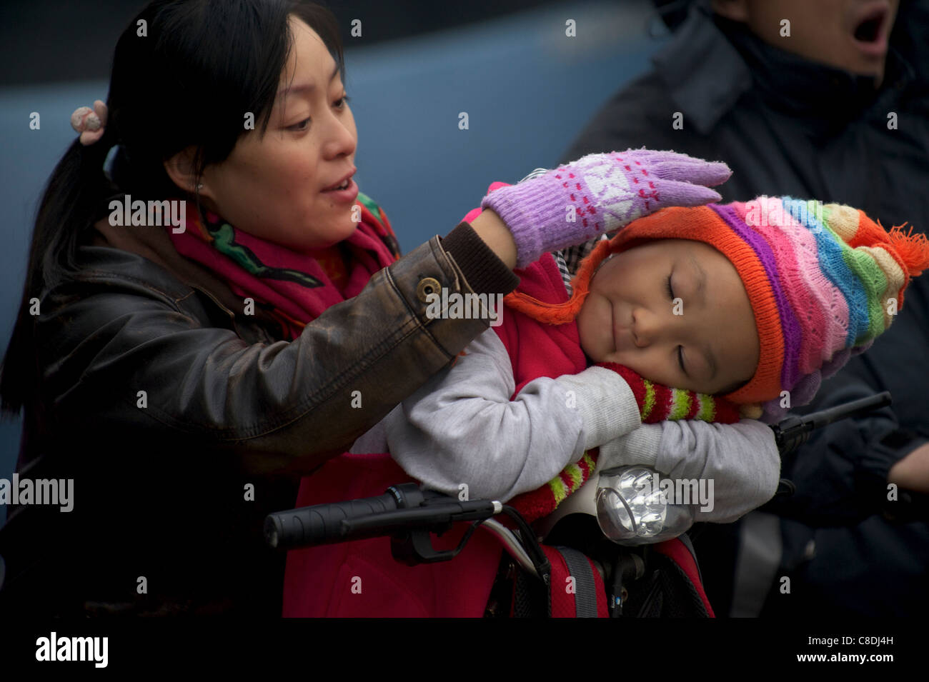 Eine chinesische Mutter berührt ihr Baby auf ein Elektrofahrrad in Peking, China. 20. Oktober 2011 Stockfoto