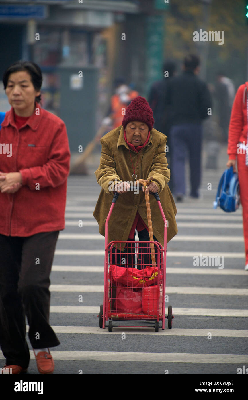 Eine alte Frau rollt einen Wagen in einer Straße in Peking, China. 20. Oktober 2011 Stockfoto