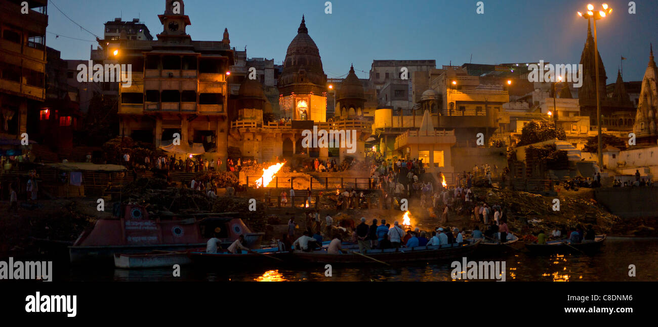 Touristen sehen Hindu Einäscherung auf Scheiterhaufen am Manikarnika Ghat, Fluss Ganges, in der Heiligen Stadt Varanasi, Benares, Indien Stockfoto