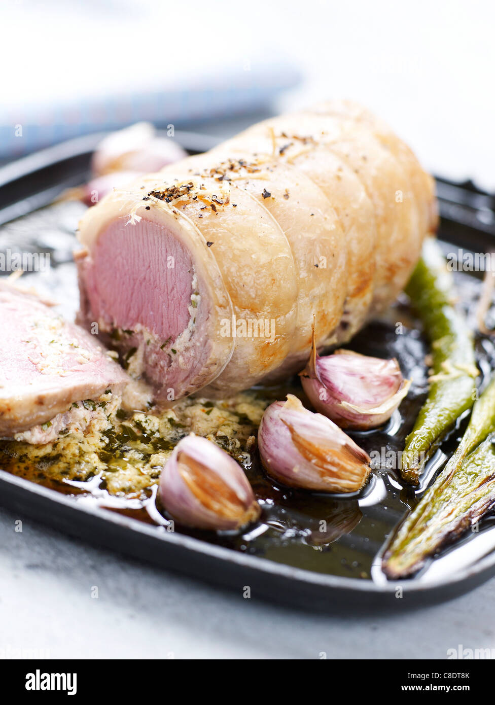 Braten-Sattel des Lammes gerollt mit Fromage Frais und Minze und gebratenem Knoblauch Stockfoto