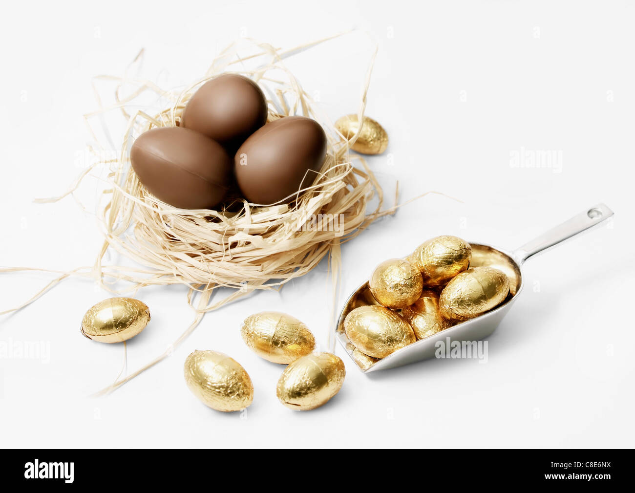 Drei Milchschokolade Eiern in ein Nest und kleinen goldenen Eiern Stockfoto