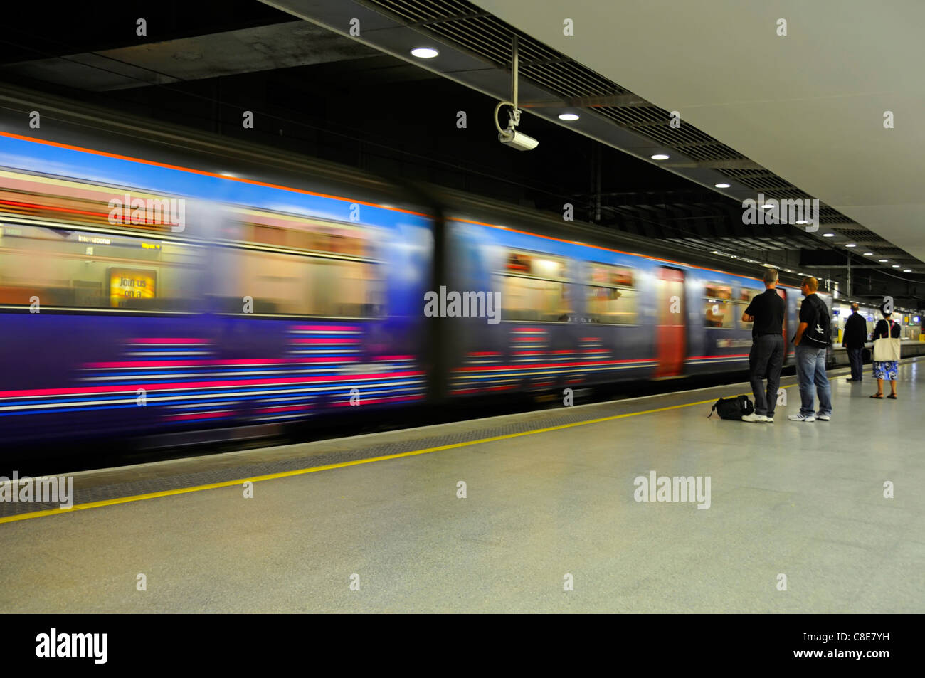 Bewegungsunschärfe von fahrenden Zügen und statischen Passagieren auf dem Bahnsteig am Bahnhof St. Pancras International für Thameslink Services in London, England, Großbritannien Stockfoto