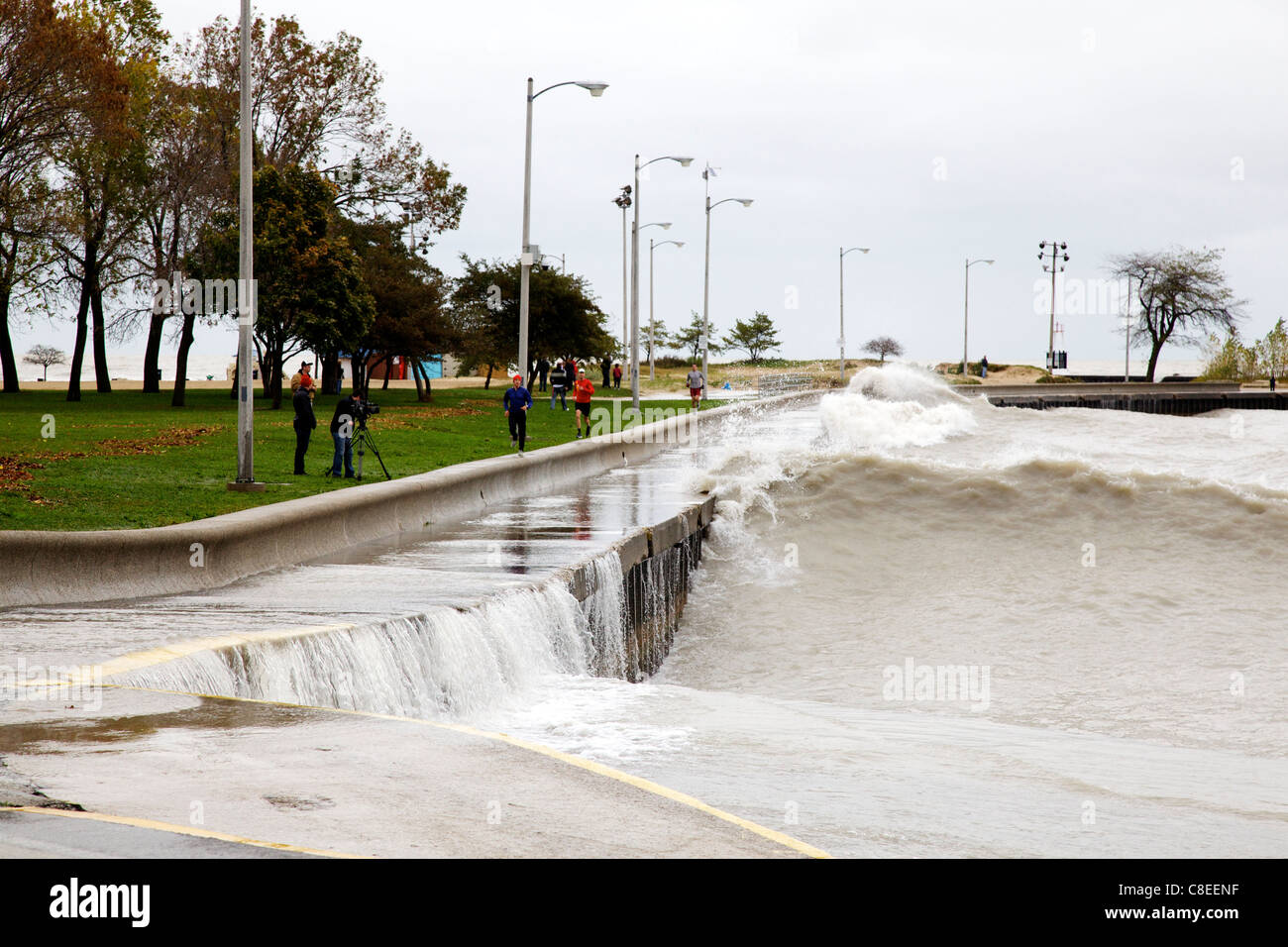 Jogger auf der Ufermauer am Nordstrand Allee und große Wellen, Chicago. 1 von 5. Stockfoto