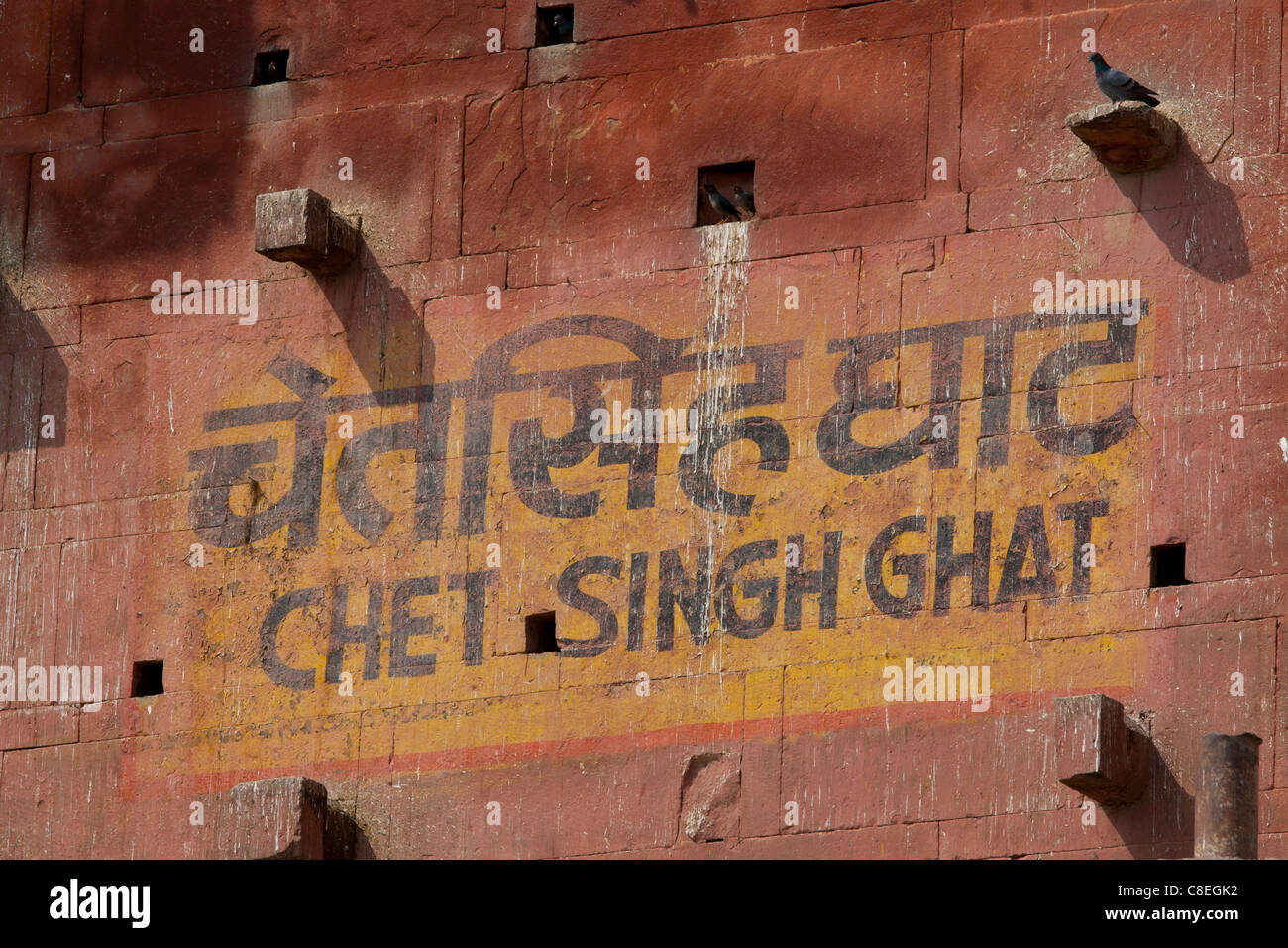 Melden Sie in indischen Schrift und Englisch für Chet Singh Ghat mit Mynah Vögel und Tauben Schlafplatz in Nischen in Varanasi, Indien Stockfoto