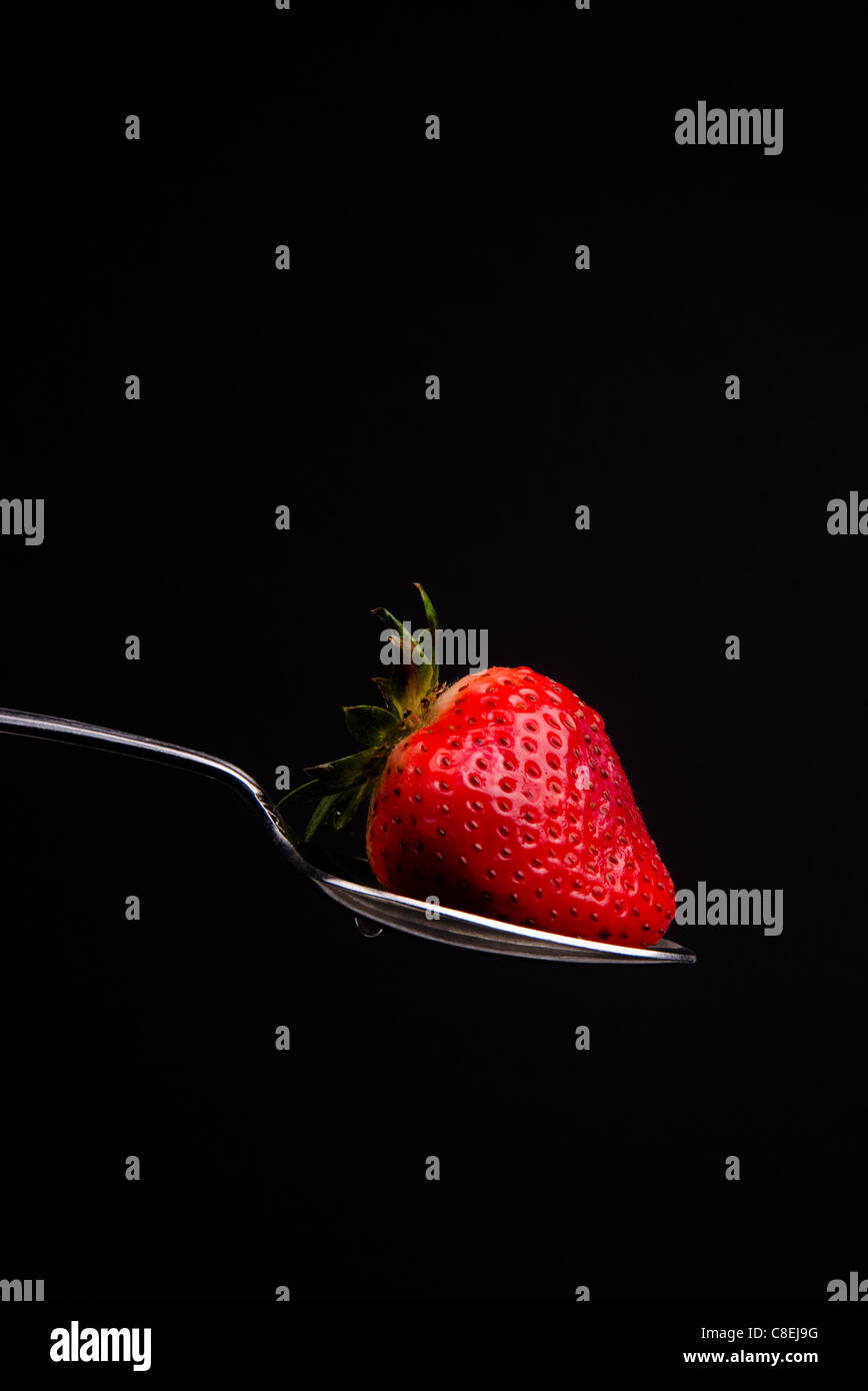 Rohe Nahrung Obst Erdbeer Milch Spritzen auf Löffel Stockfoto