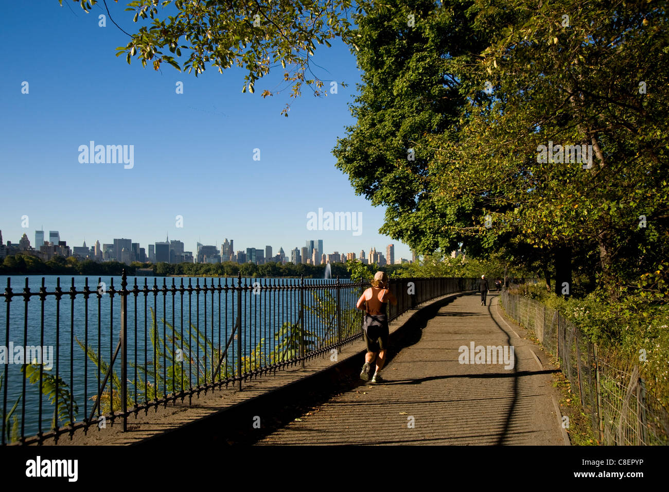 Jogger auf dem richtigen Weg rund um den Stausee im Central Park und die Skyline der Stadt in den Hintergrund, New York City, New York State, USA Stockfoto