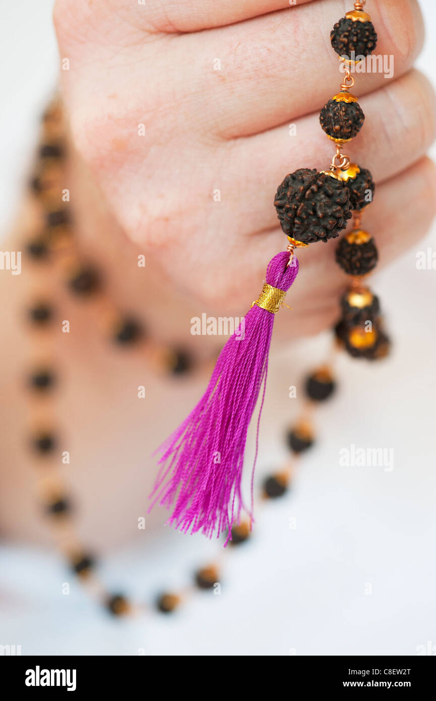 Mans Hand mit indischen Rudraksha / Japa Mala Gebet gegen weiße Perlen Stockfoto