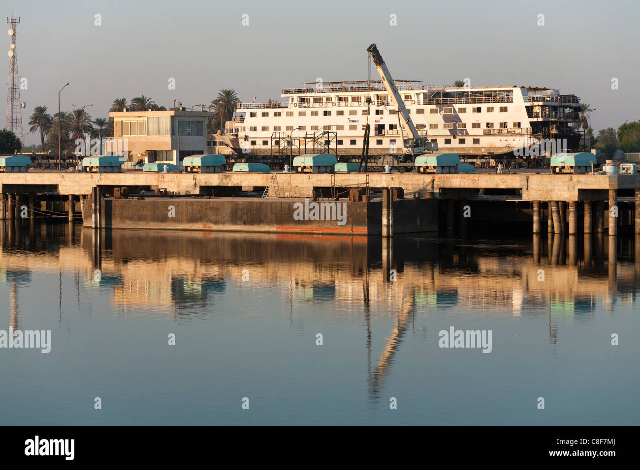 Ein Teil des Nil Flusses mit cruise Boot im Trockendock, mit Kränen und Gebäude spiegelt sich in der Flaute Wasser, Ägypten Stockfoto