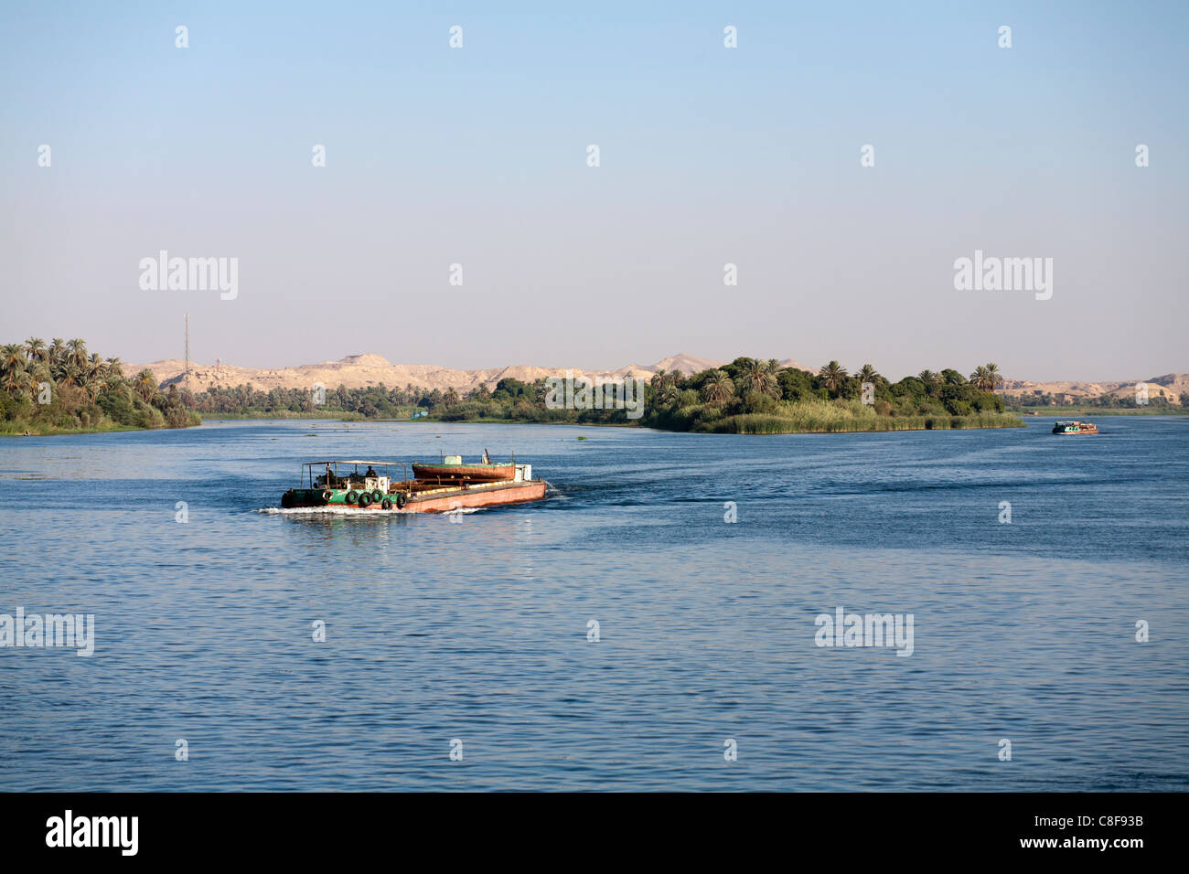 Einem breiten Abschnitt des Nil mit Schlepper Boot segeln niedrig im Wasser Weg von der Kamera mit entfernten Wüstenberge, Ägypten Stockfoto