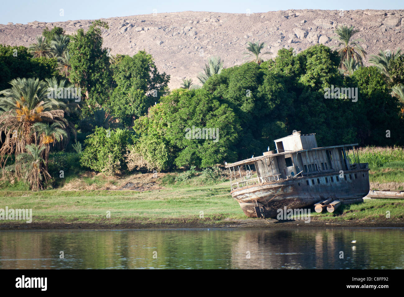 Ein Teil der Nil-Ufer mit verlassene verfallene Stahlrumpf der Fähre Boot Rost entfernt am Rande grasbewachsenen, Ägypten Stockfoto
