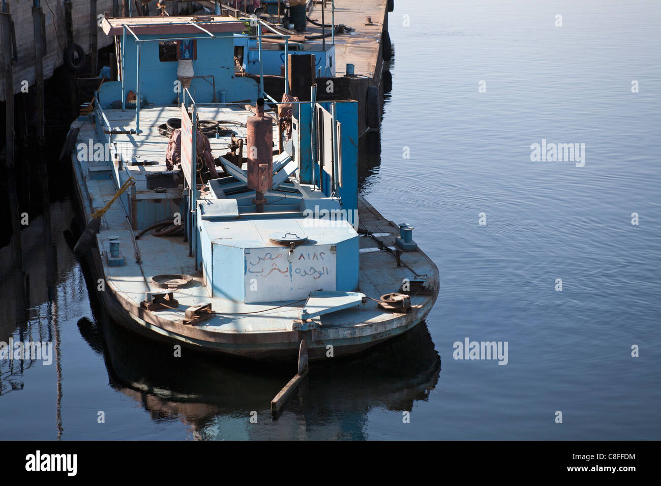 Leicht nach unten auf einem Schlepper arbeiten vertäut Heck gerichtete Kamera am Steg mit Reflexion in ruhigem Wasser, Fluss Nil Ägypten Stockfoto