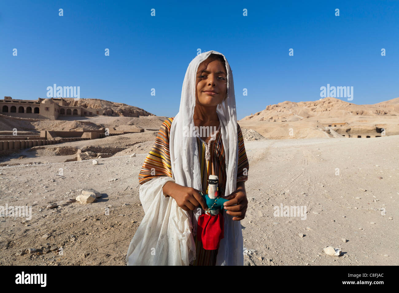 Ein ägyptische Mädchen im Besitz einer Hand gemacht Puppe mit Wüste im Hintergrund Luxor, Ägypten Stockfoto