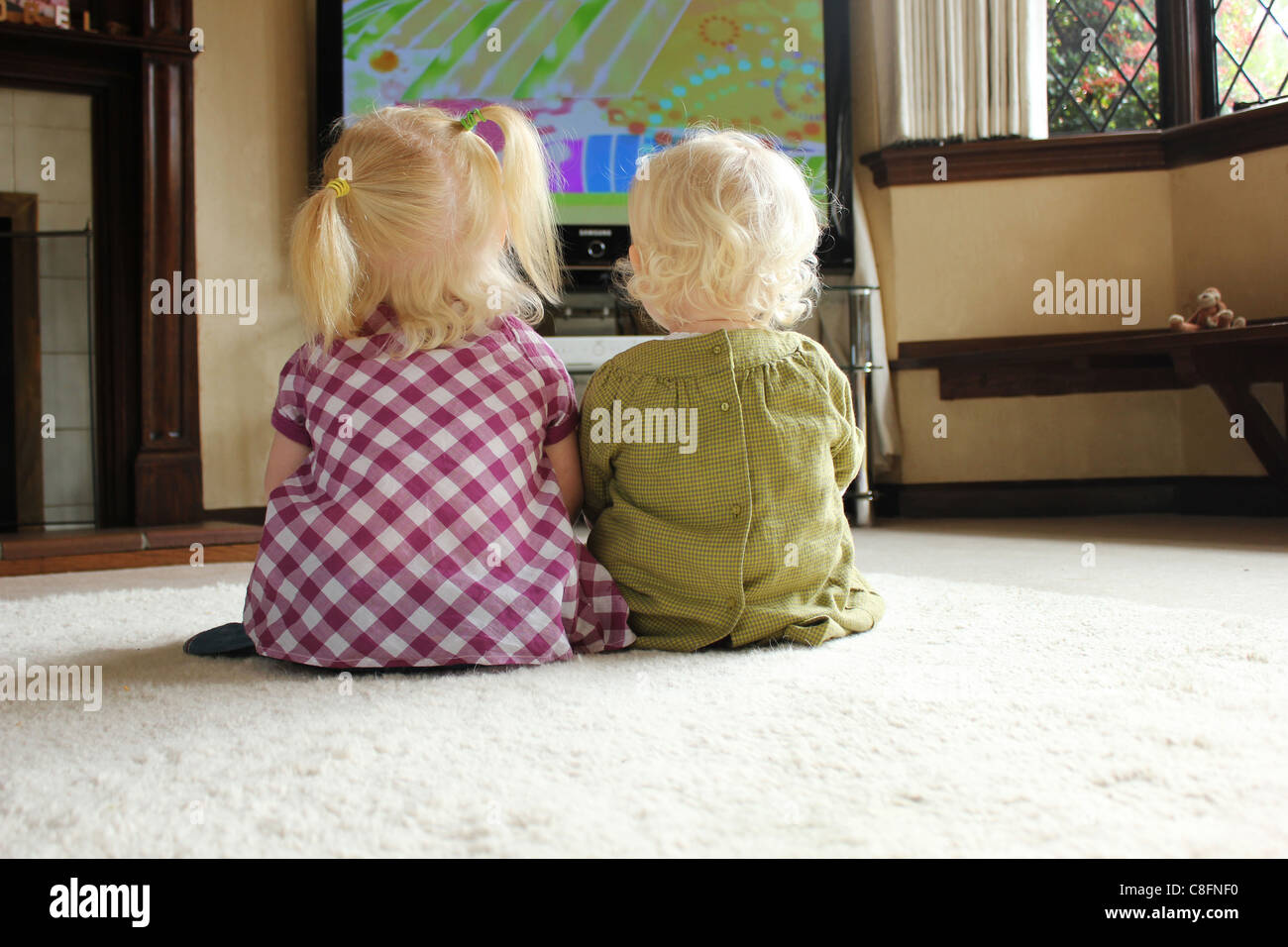 Schwestern beobachten Fernseher zusammen sitzen, auf einem Teppich Stockfoto