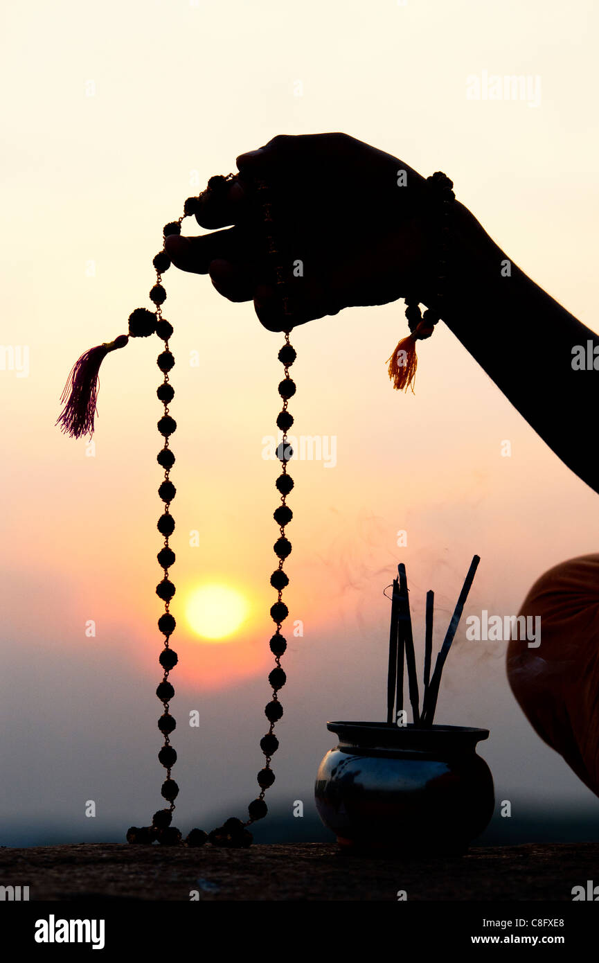 Mans Hand mit indischen Rudraksha / Japa Mala Gebet Perlen und Weihrauch. Silhouette Stockfoto