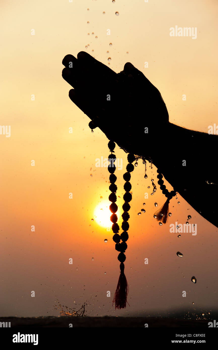 Mans Gebet Hände halten indischen Rudraksha / Japa Mala Gebetskette. Silhouette Stockfoto