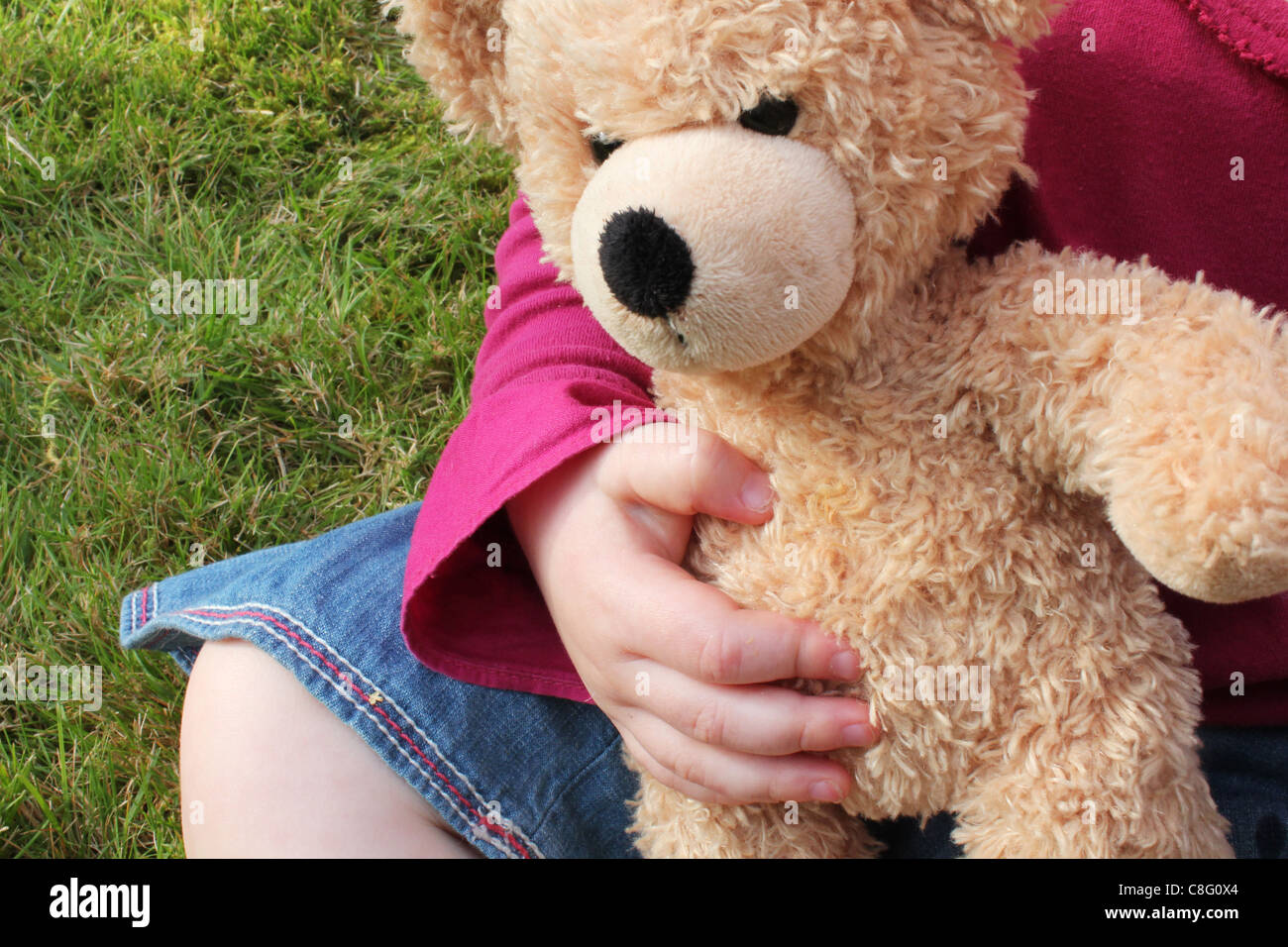 kleines Mädchen kuscheln Teddybär im Garten Stockfoto