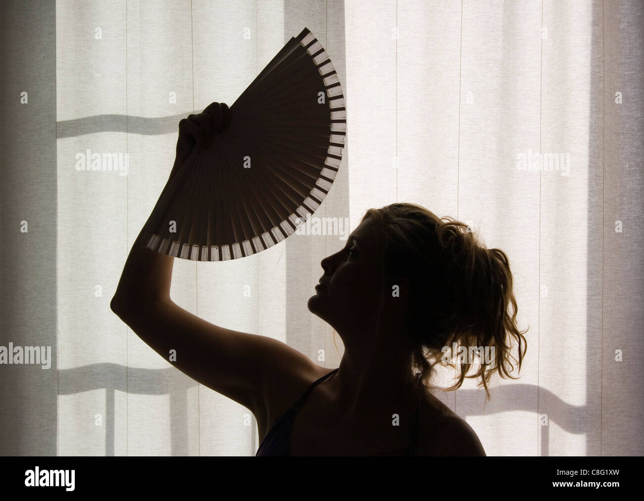 Silhouette der jungen Frau mit Fächer. Stockfoto