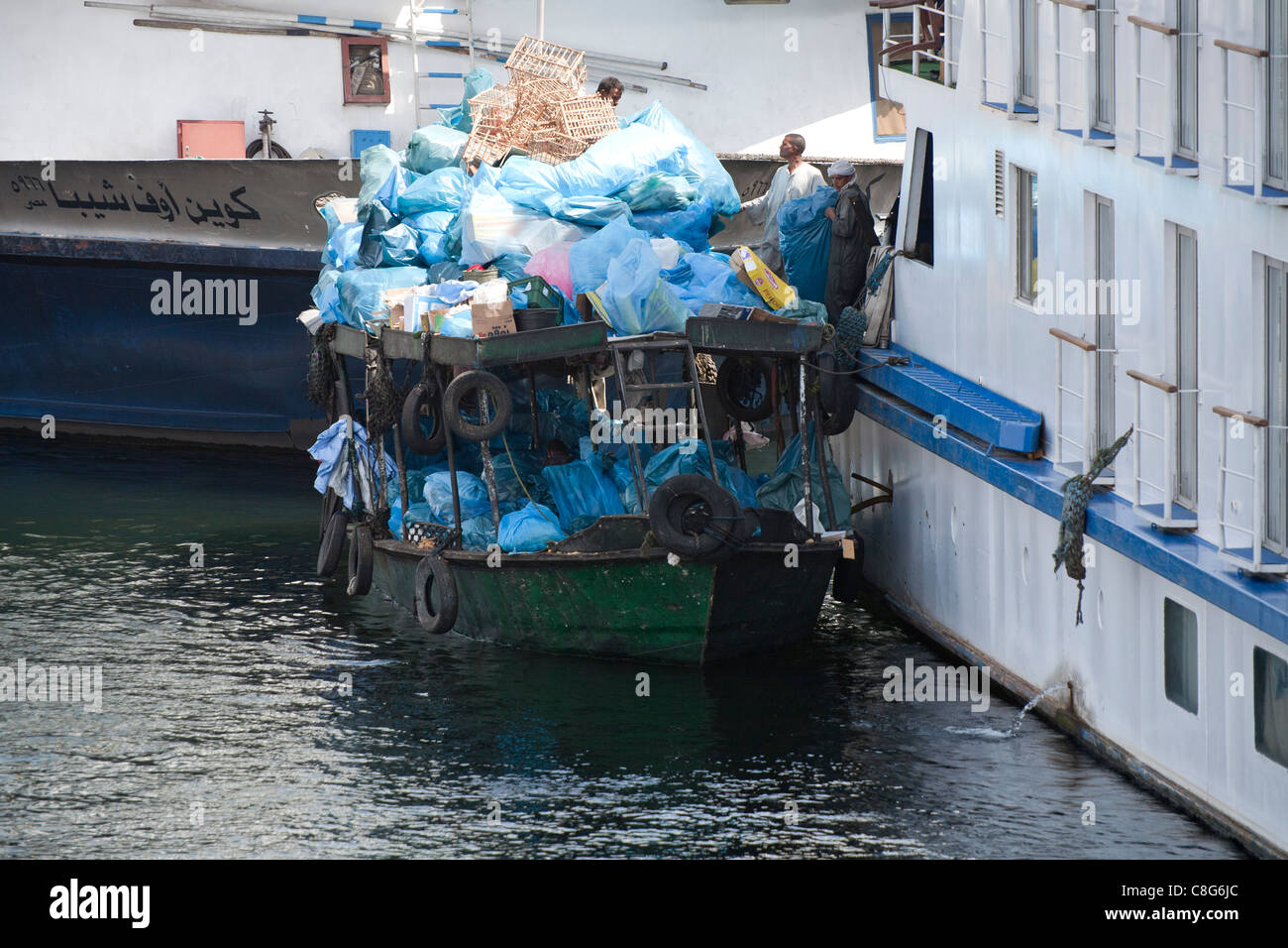 Ein Müll Sammlung Boot entfernen voll blaue Müllsäcke festgemacht an der Seite einer Nil-Kreuzfahrt-Schiff, Ägypten Afrika Stockfoto