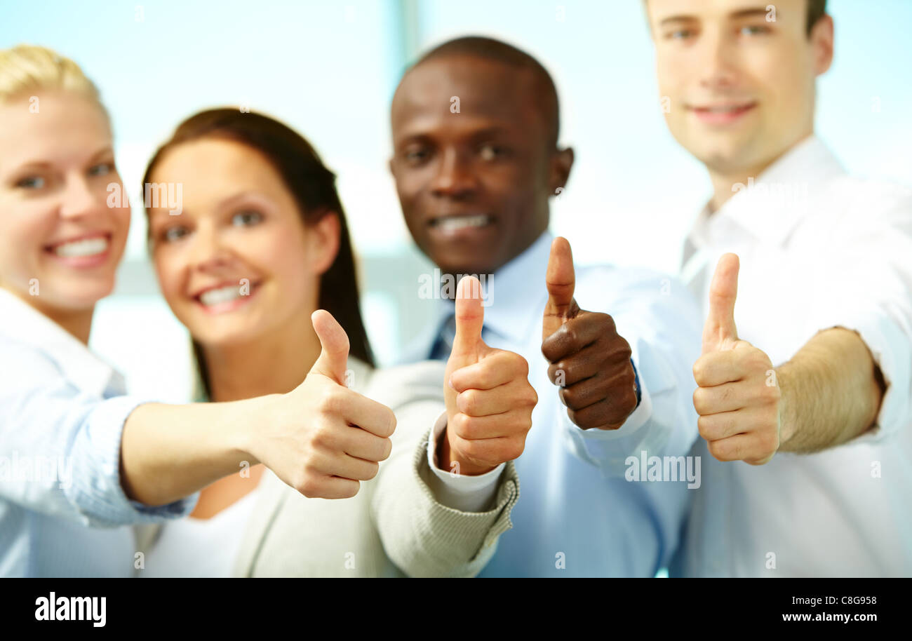 Vier Geschäftsleute zeigen, Daumen und lächelt in die Kamera Stockfoto