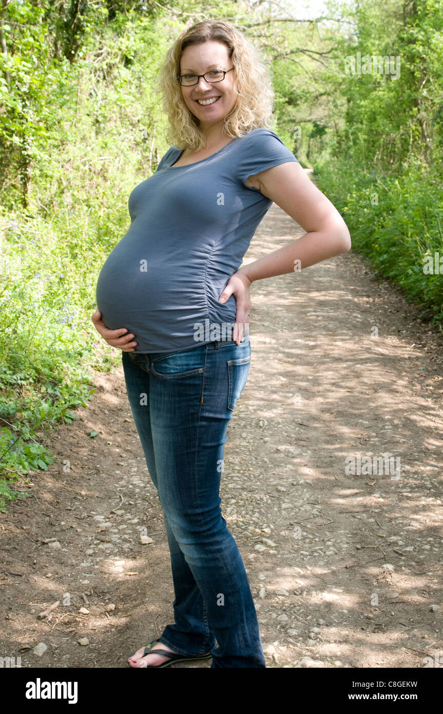 Porträt einer schwangeren Frau zu Fuß entlang der Landstraße Stockfoto