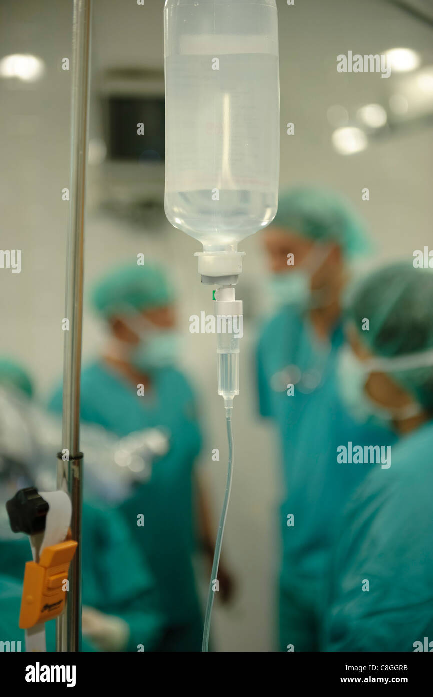Drei Ärzte hinter einer IV-Tasche im Krankenhaus verschwommen Stockfoto