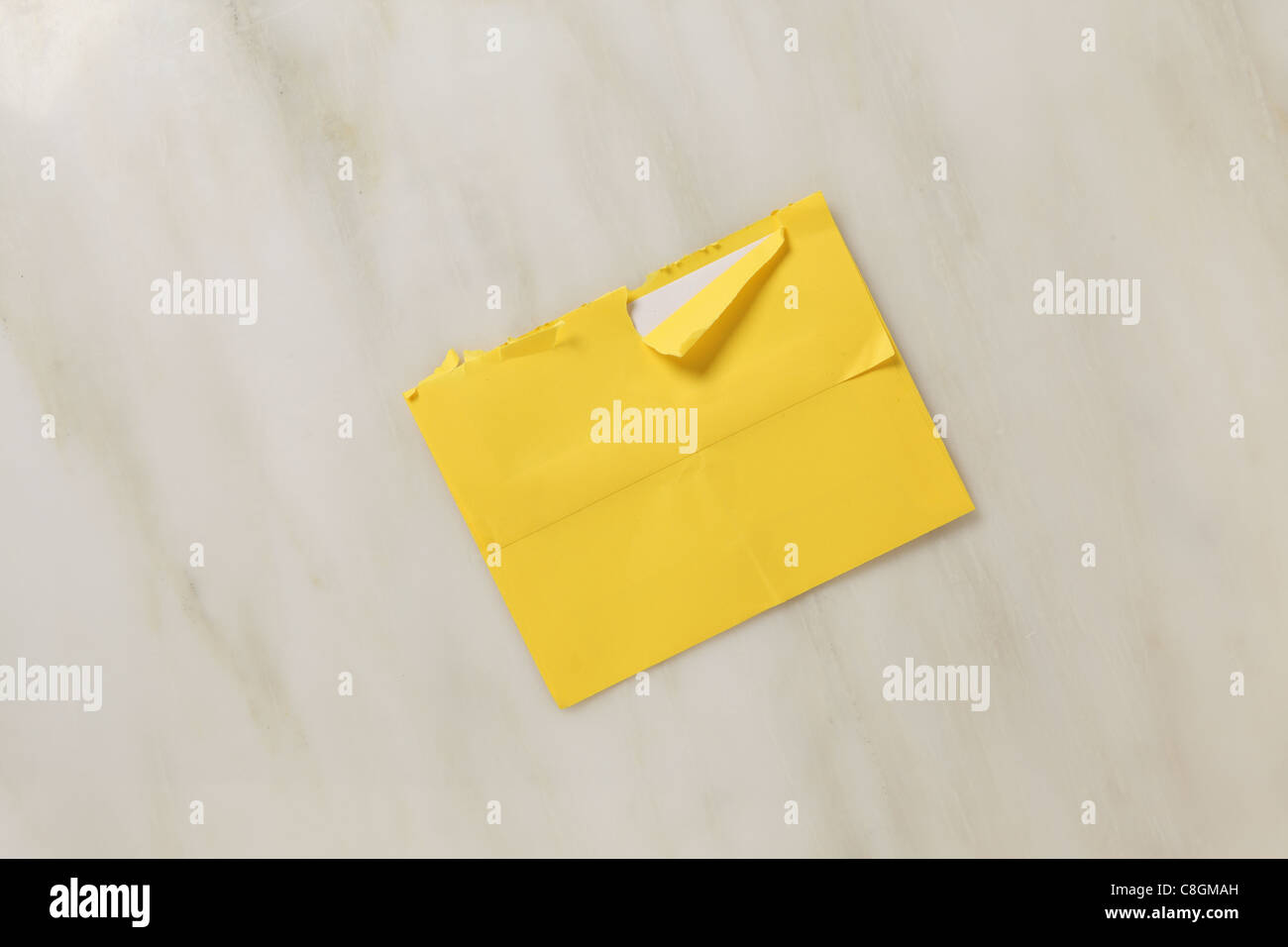 Eine gebrauchte und leicht zerrissen offen Postumschlag auf ein Marmor Oberfläche hell gelber farbiger Umschlag Stockfoto