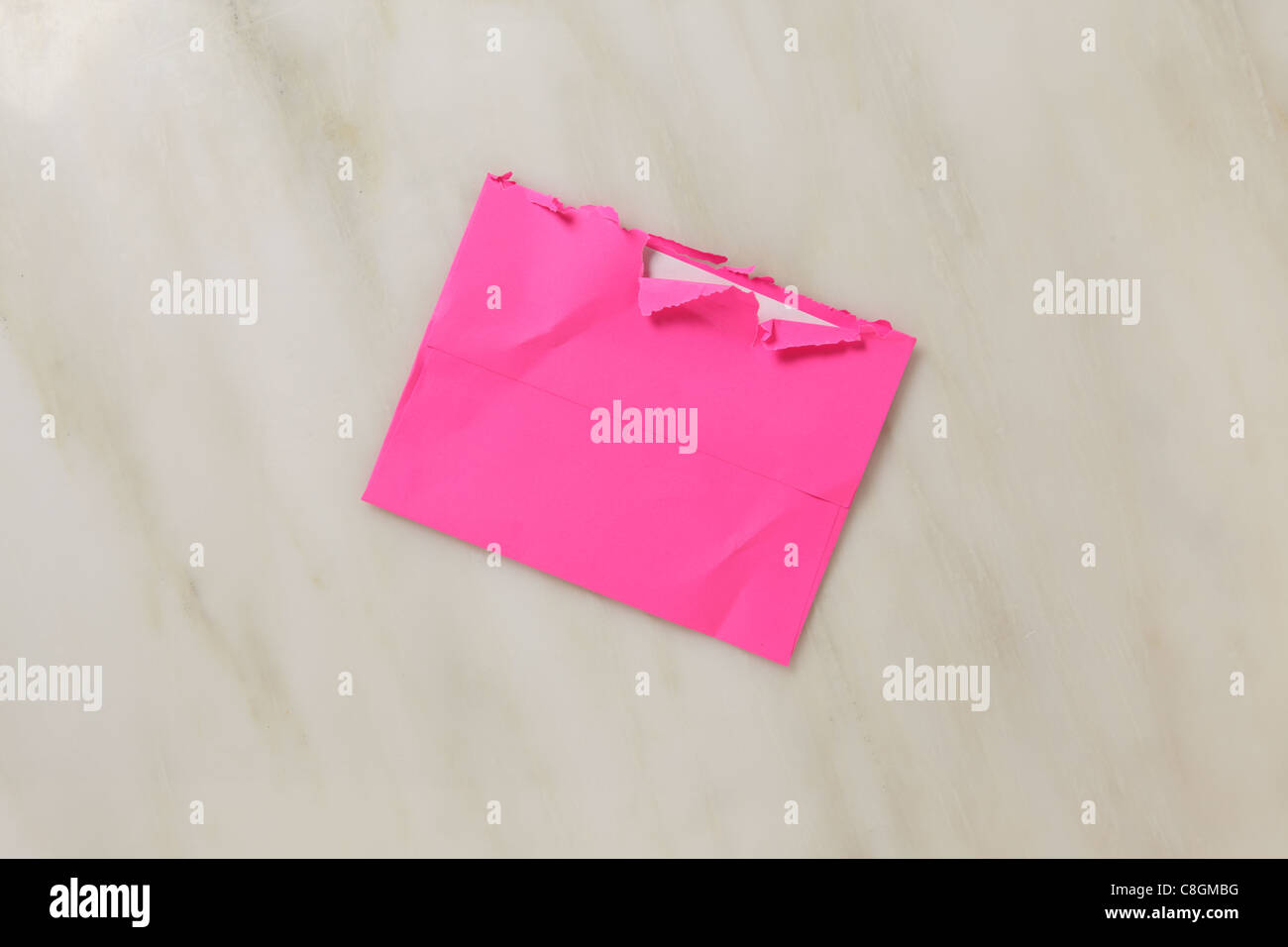 Eine gebrauchte und leicht zerrissen offen Postumschlag auf einem Marmor Oberfläche hell rosa farbigen Umschlag Stockfoto