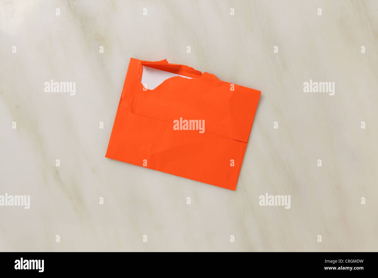Eine gebrauchte und leicht zerrissen offen-Postumschlag auf Marmor Oberfläche. Leuchtend orange farbigen Umschlag Stockfoto