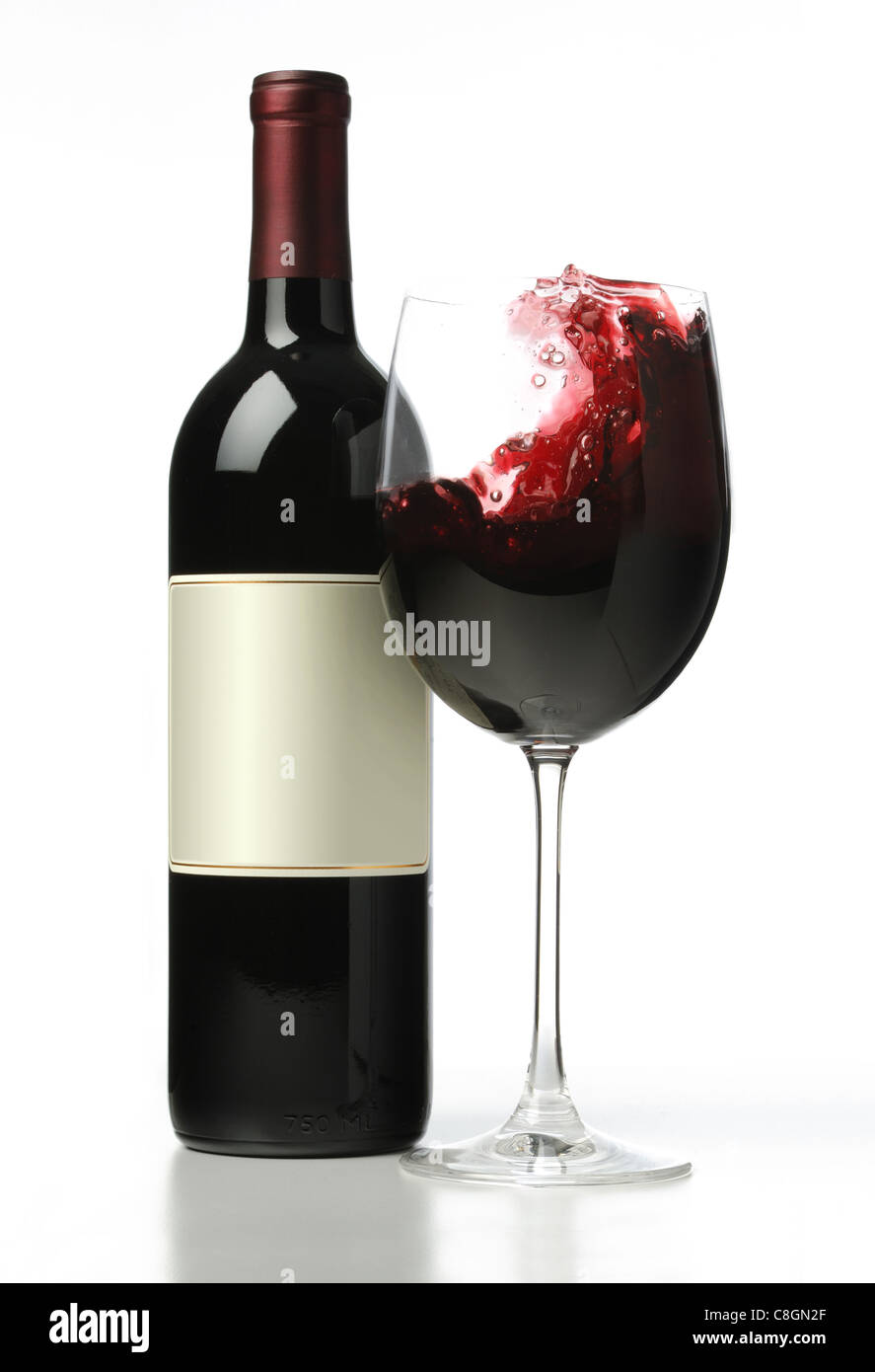 Eine Flasche Rotwein mit einem Glas Rotwein Plantschen im Inneren des Glases. Stockfoto