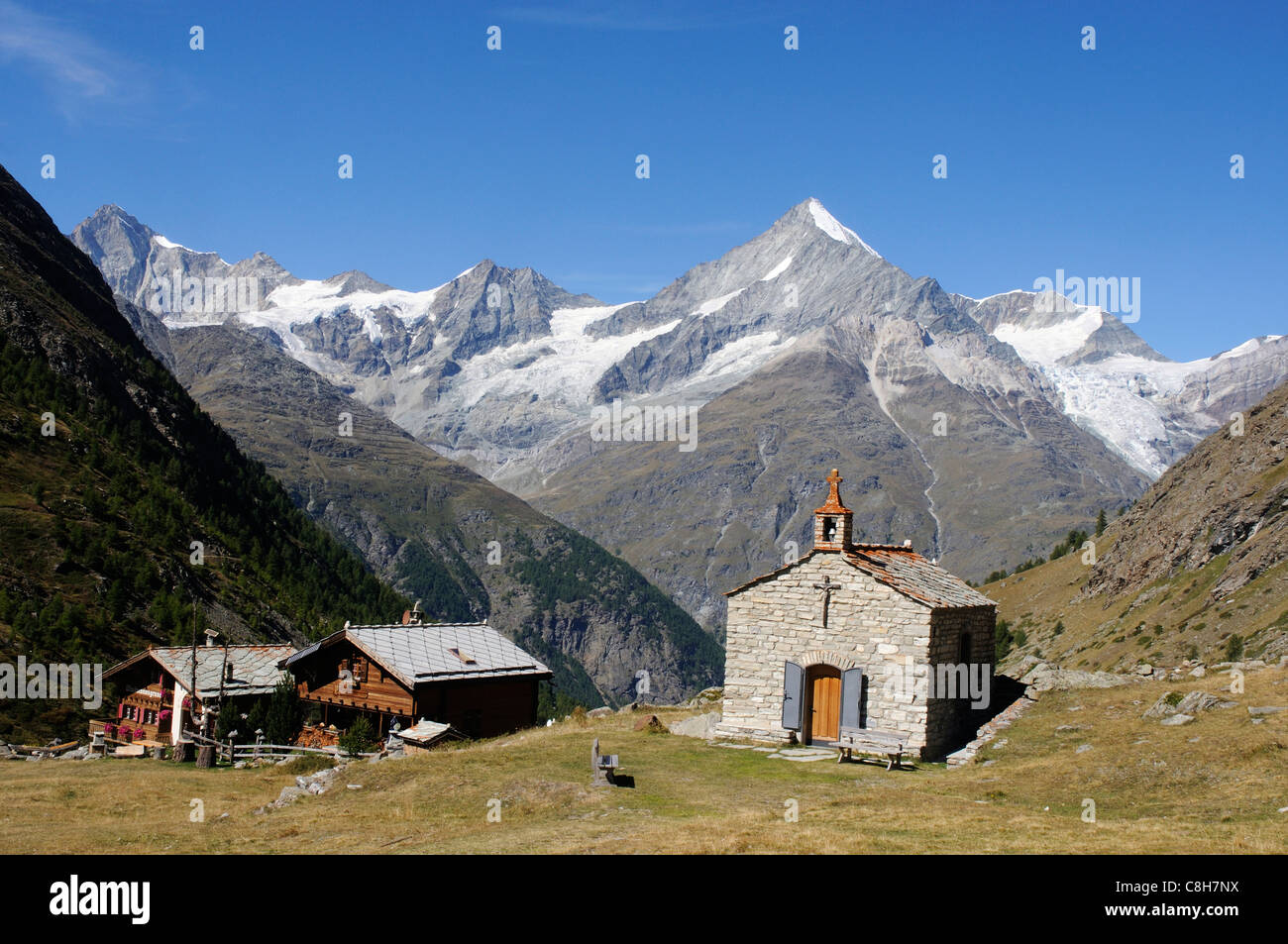 Eine kleine Kapelle und zwei Chalets im Wallis auf die Schweizer Alpen mit dem Weisshorn über hohe Stockfoto