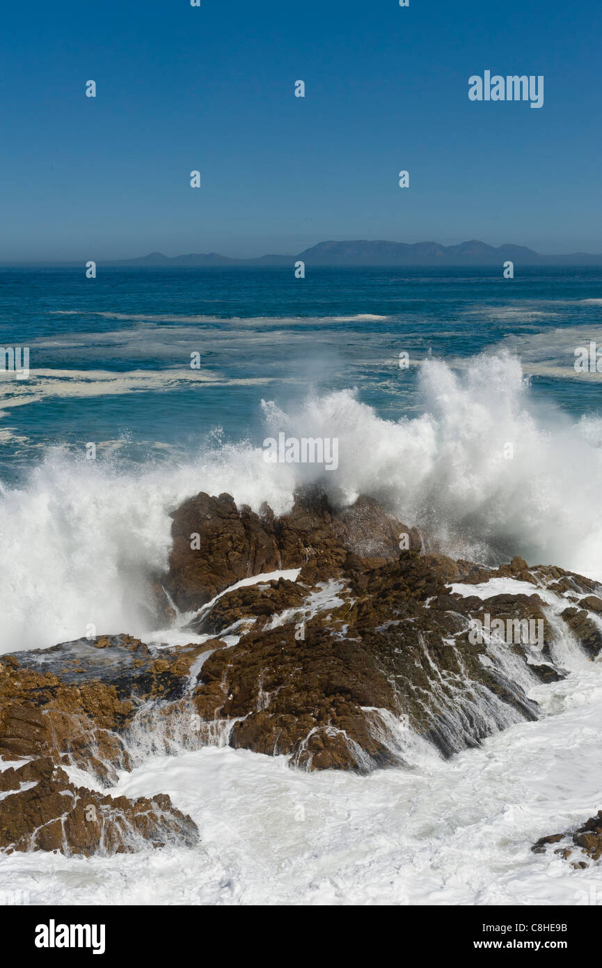 Wellen brechen auf den Felsbrocken entlang Route 44 Tafelberg im Hintergrund Südafrika Stockfoto