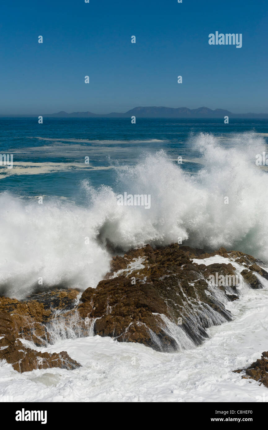 Wellen brechen auf den Felsbrocken entlang Route 44 Tafelberg im Hintergrund Südafrika Stockfoto