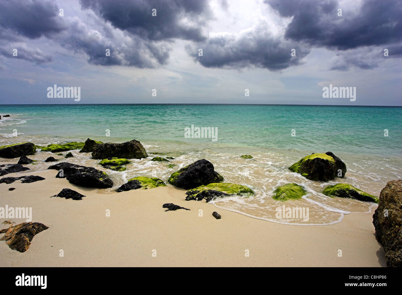 Blick auf das Meer über die Felsen am Druif Beach in Aruba, das Karibische Meer erstreckt sich auf den Abstand, ein bewölkter Himmel overhead Stockfoto